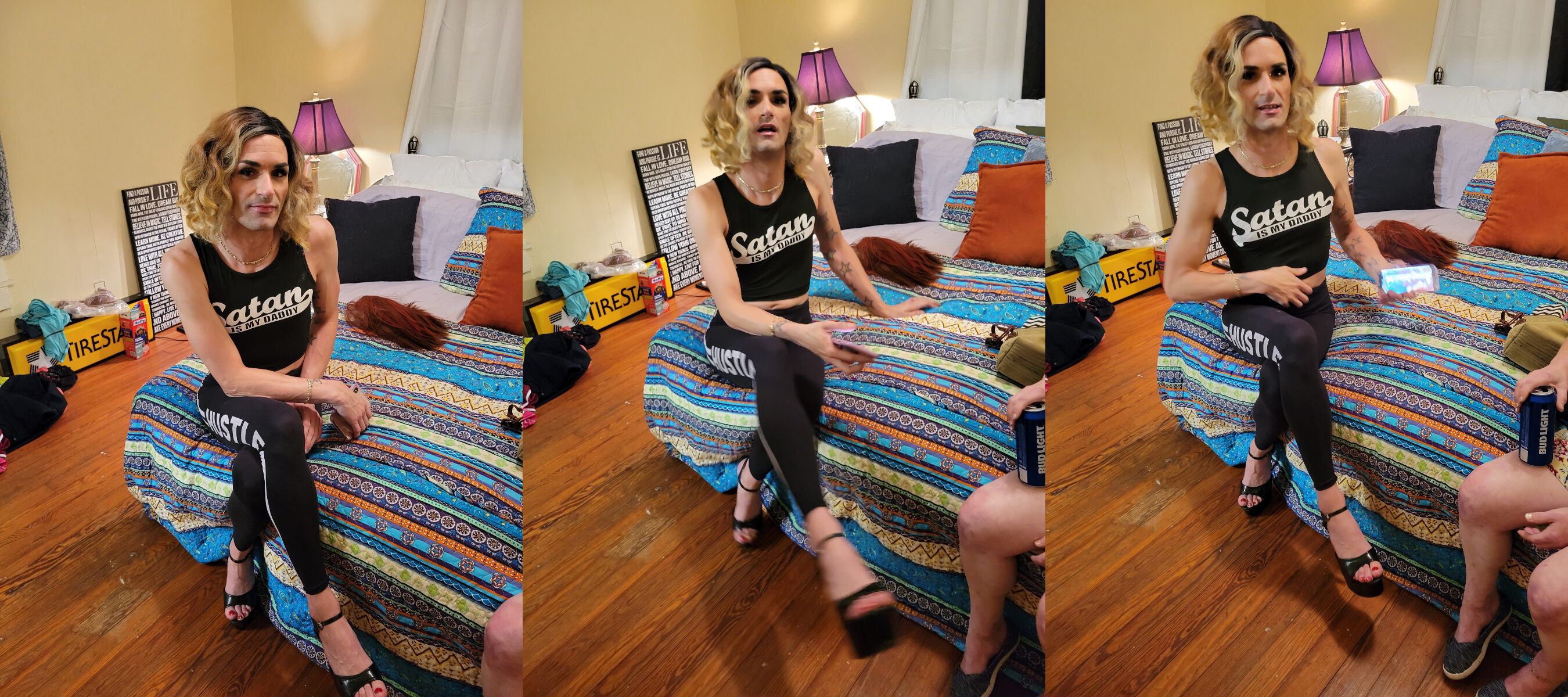 Hank Hank, the cross dressing satanic cultist, dressed as a girl and wearing makeup, sporting a 5 o clock shadow, and wearing a shirt that says satan is my daddy. His clothes are all black, skimpy, and showing skin, as he is holding his cell phone, and there is a can of bud light creeping into in the side view of the photo.